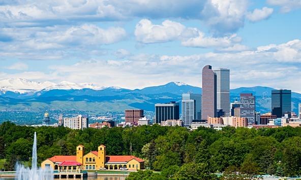Denver Colorado view, tall buildings and a city park in the foreground with mountains in the background